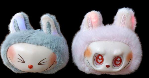 Two plush bunny masks on black background.