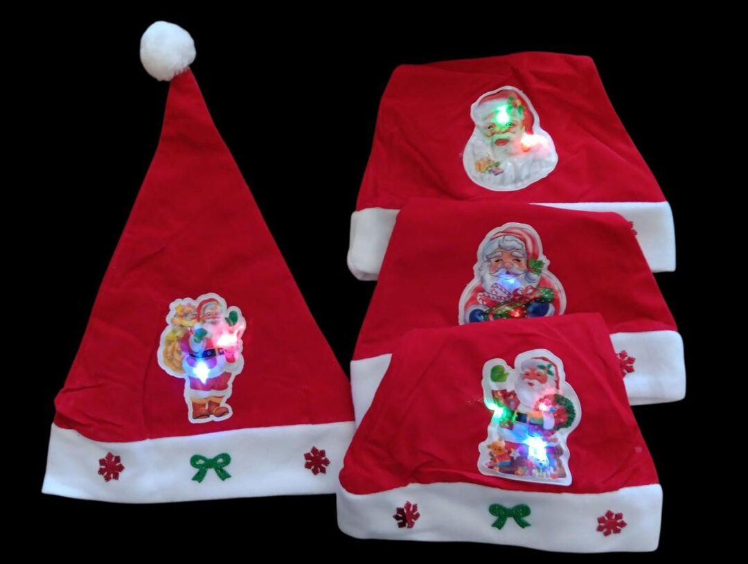Three red Santa hats decorated with festive stickers on a white surface.