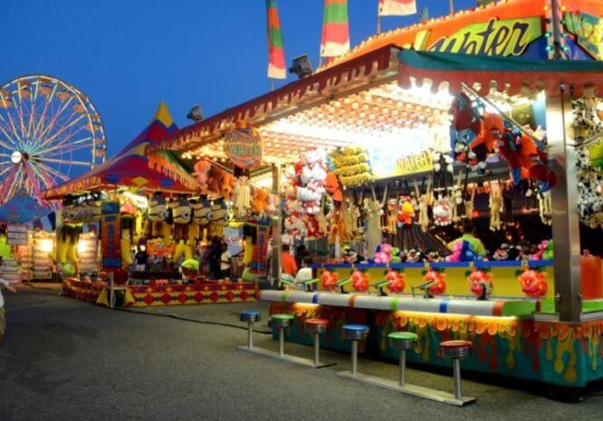 Colorful carnival game booth with prizes at dusk.